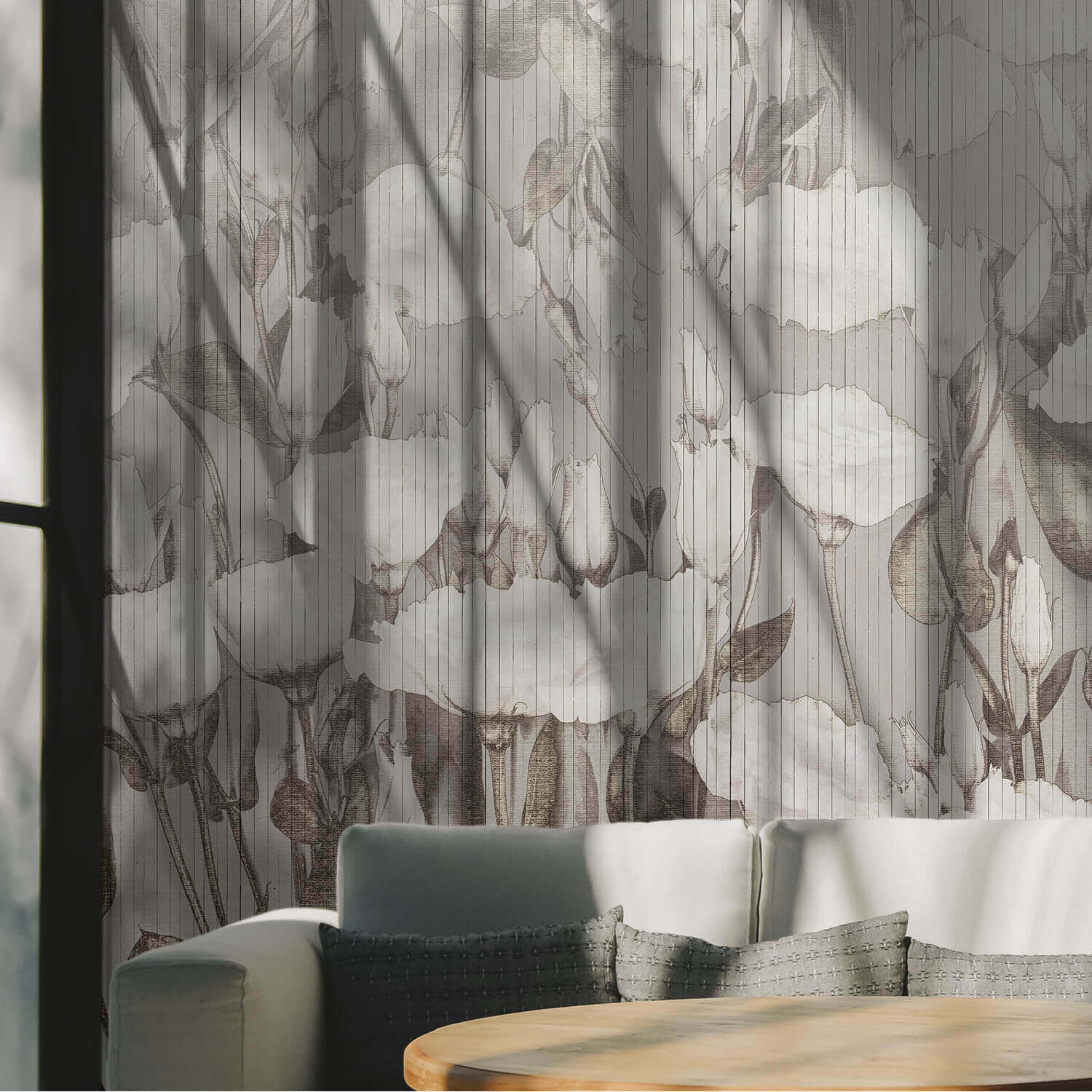 Soggiorno luminoso. La parete è rivestita con carta da parati in tonalità neutre e crema, con grandi illustrazioni di fiori in stile bozzetto e linee verticali. Forte contrasto di luci e ombre proiettate dalle finestre.
